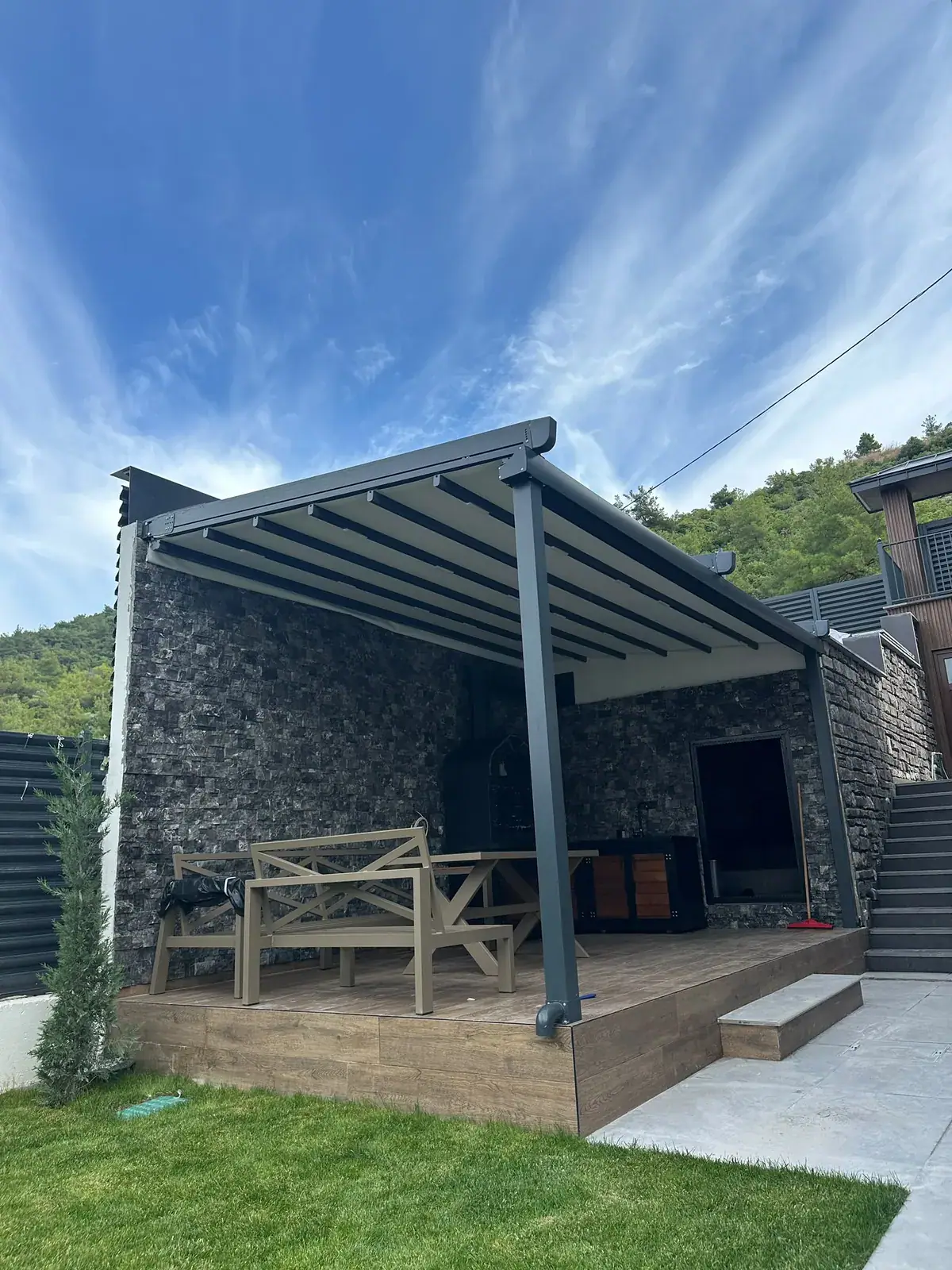 Taş duvarlı bahçe oturma alanına kurulan pergola tente